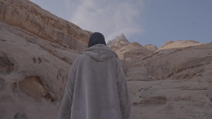 فتاة تسير نحو الجبل في الصحراء، لقطة من الخلف.