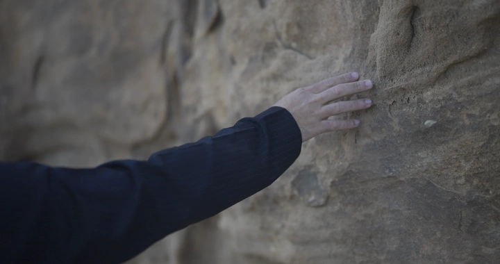 يد تلمس سطح جبل صخري، لقطة مقربة.