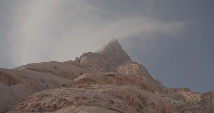 قمة جبل المسمى في حائل محاطة بالغيوم، لقطة من الأسفل.