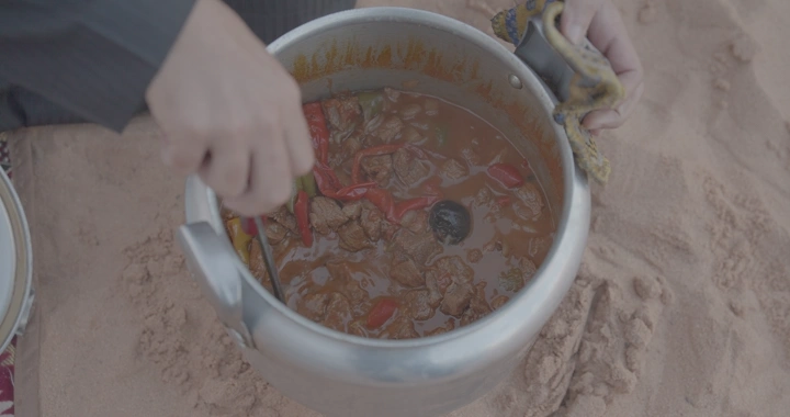 طهي مقلقل لحم في قدر ضغط على الرمال، لقطة مقربة.