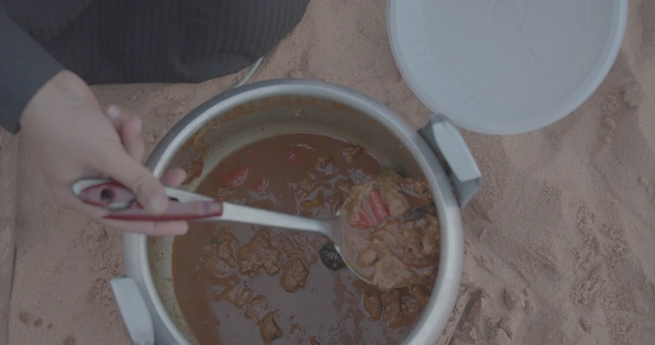 مقلقل لحم في قدر ضغط على الرمال، لقطة علوية.