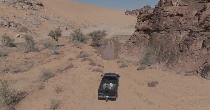 سيارة دفع رباعي في صحراء شعيب تحت سماء صافية، لقطة جوية.