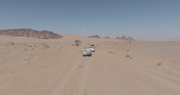 سيارات تسير في صحراء جبال المسمى في حائل، لقطة جوية.