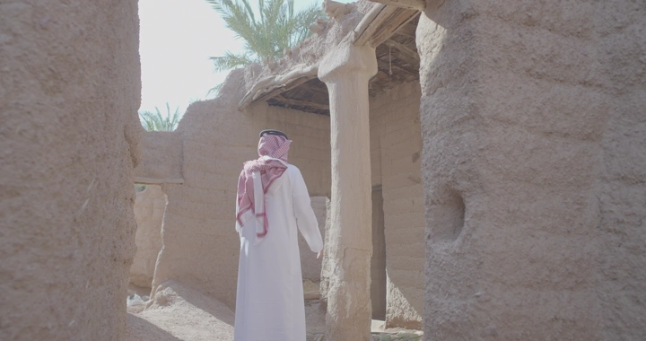 رجل يرتدي ثوبًا في بيت طين قديم، لقطة نهارية.