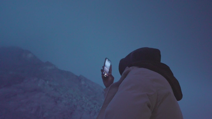 شخص يستخدم هاتفًا في جبال عقدة حائل الضبابية، لقطة ليلية.