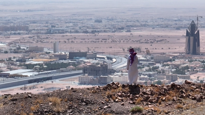 شخص يقف على تلة تطل على مدينة حائل، لقطة نهارية.