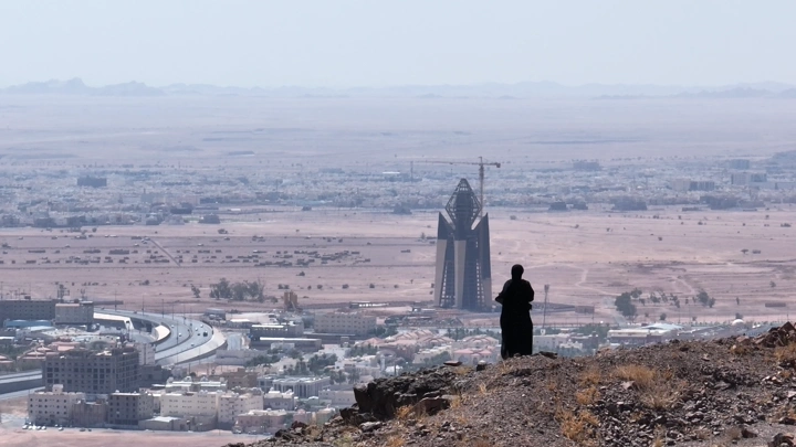 شخص يقف على تلة تطل على مدينة حائل، لقطة من بعيد.