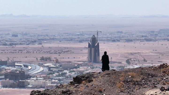 شخص يقف على تلة تطل على مدينة حائل، لقطة بعيدة.