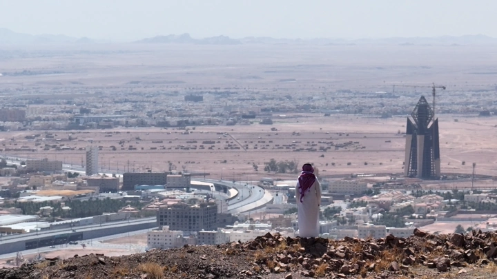 شخص يقف على تلة تطل على مدينة حائل، لقطة بعيدة.