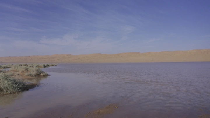 بحيرة في صحراء النفود تحت سماء زرقاء، لقطة بانورامية.