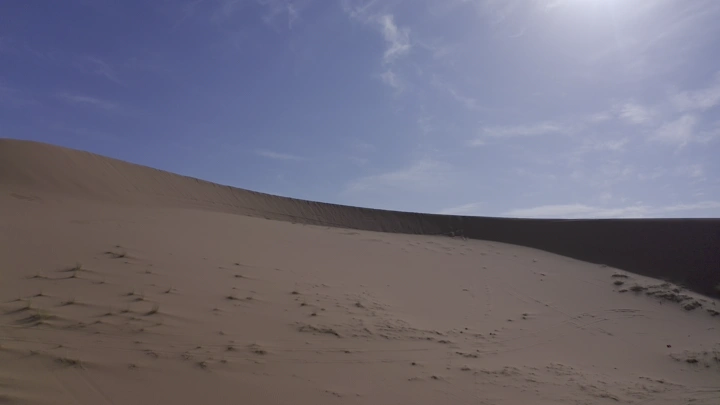 كثبان رملية في نايلات حائل تحت سماء زرقاء، لقطة واسعة.