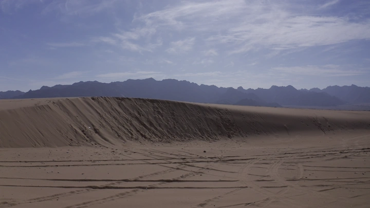 كثبان رملية في نايلات حائل تحت سماء زرقاء، لقطة نهارية.