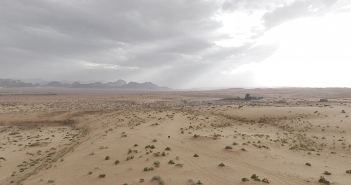 صحراء واسعة تحت سماء غائمة، لقطة جوية.