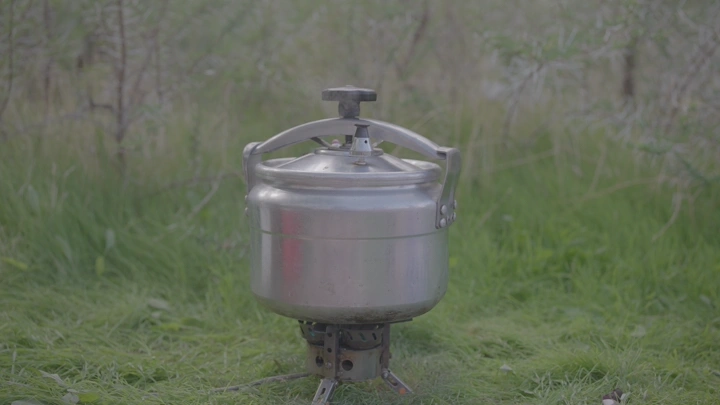 قدر ضغط معدني في الهواء الطلق على العشب، لقطة نهارية.