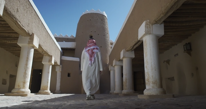 شخص يرتدي الزي السعودي في قلعة عيرف بحائل، لقطة من الخلف.