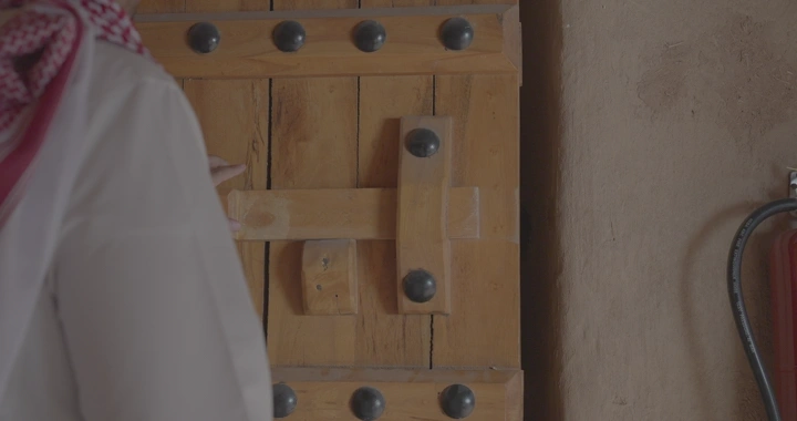 باب خشبي تقليدي يقفله شخص يرتدي ثوب، لقطة قريبة.