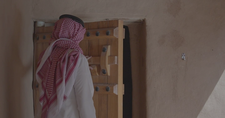 رجل يرتدي الزي التقليدي يغلق باب خشبي، لقطة خارجية.