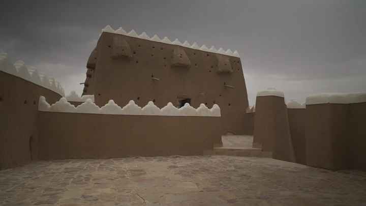 فتاة تمشي داخل قلعة اعيرف في حائل تحت سماء غائمة، لقطة أرضية.