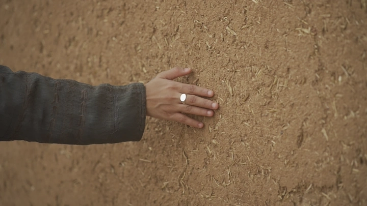 يد تلمس جدار طيني، لقطة قريبة.