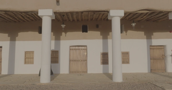 واجهة قصر القشلة في حائل تحت ضوء الشمس وامرأة تمشي في اروقتها، لقطة أمامية.