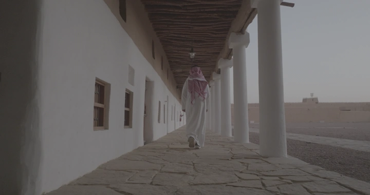 رجل يسير في ممر قصر القشلة بحائل، لقطة من الخلف.