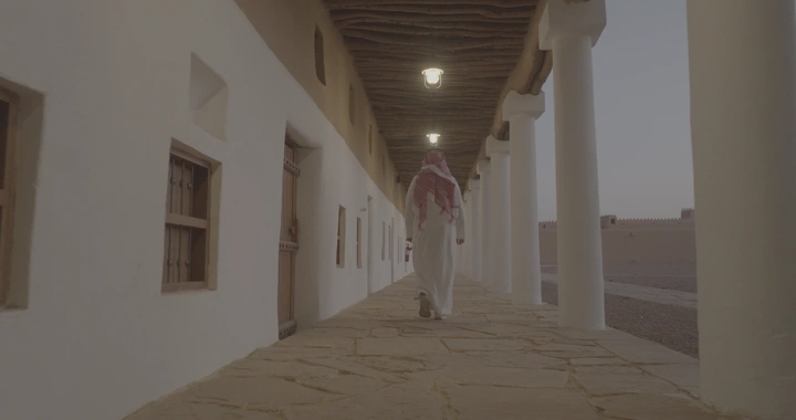 شخص يمشي في ممر قصر القشلة بحائل، لقطة من الخلف.