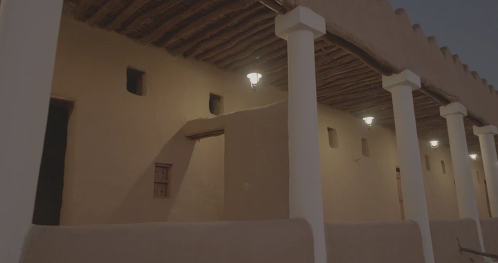 واجهة قصر القشلة في حائل ورجل يمشي في اروقتها عند الغروب، لقطة ليلية.