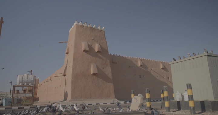 قصر القشلة في حائل تحت السماء الزرقاء مع حمام يطير، لقطة نهارية.