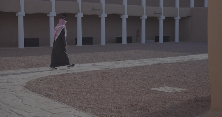 رجل يمشي في ساحة قصر القشلة بحائل، لقطة جانبية.