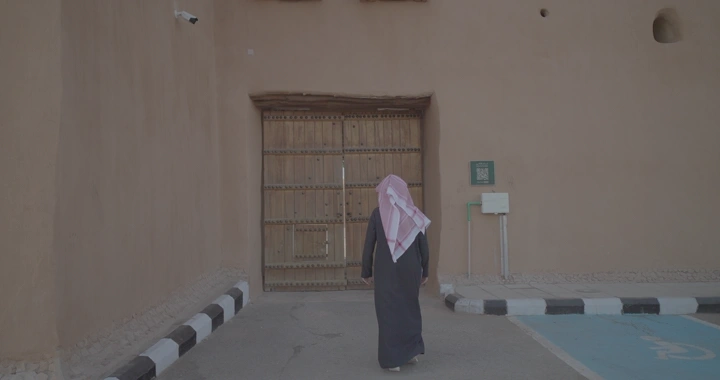 شخص يمشي نحو بوابة قصر القشلة في حائل، لقطة من الخلف.