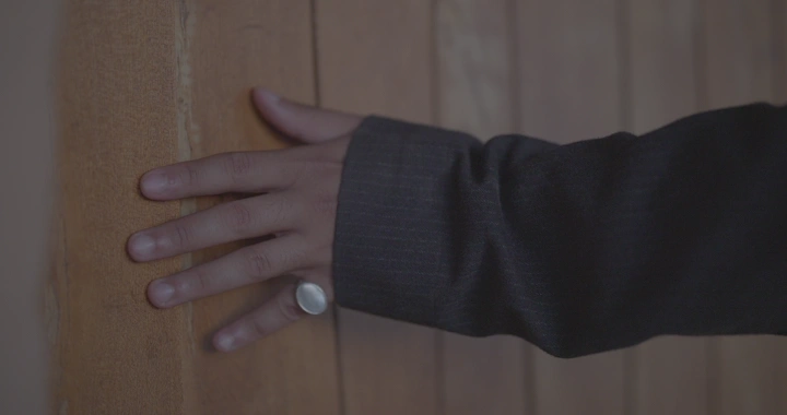 يد تلمس باب خشبي وجدار طيني، لقطة مقربة.