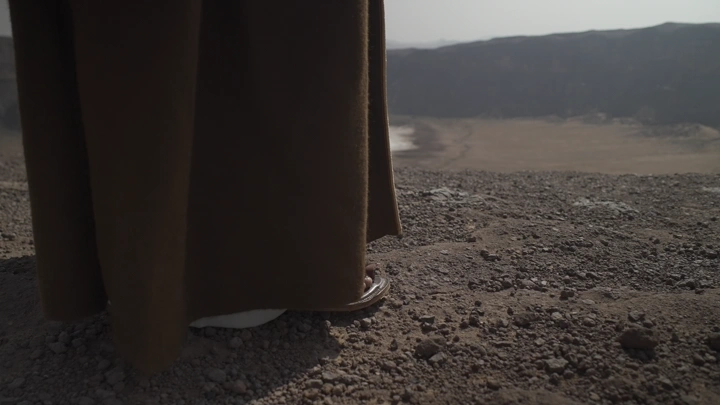 شخص يمشي على حافة فوهة بركان الهتيمه في حائل، لقطة قريبة.