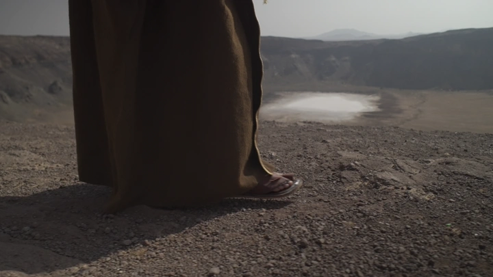 شخص يمشي على حافة فوهة بركان الهتيمه في حائل، لقطة قريبة.