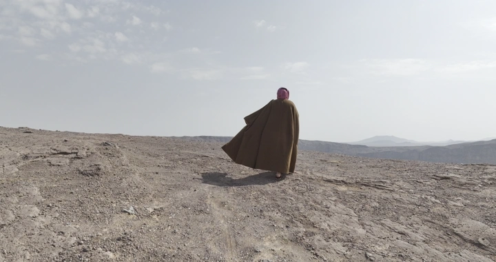 شخص يسير على حافة فوهة بركان الهتيمه بحائل، لقطة من الخلف.