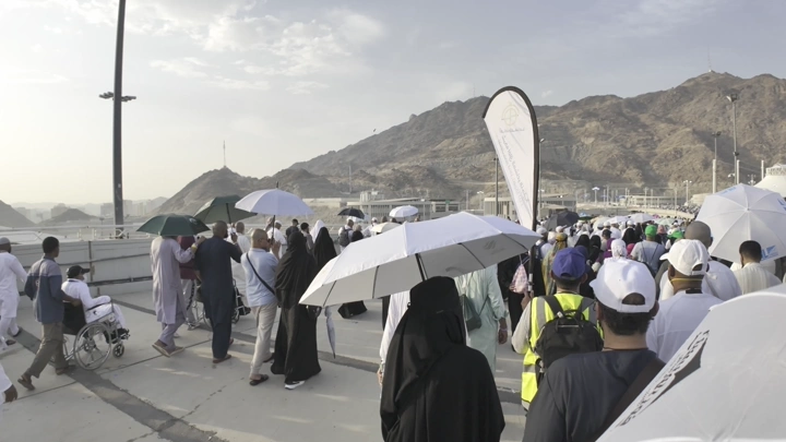 حجاج يسيرون على جسر الجمرات في مشعر منى، لقطة نهارية.