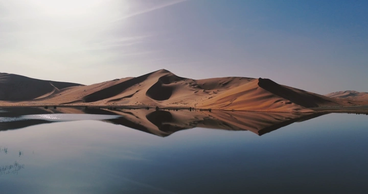 بحيرة في صحراء الربع الخالي تحت سماء زرقاء، لقطة جوية.