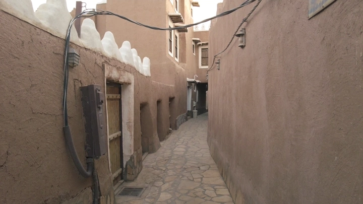ممر ضيق في قرية أشيقر التراثية، لقطة من مستوى الشارع.