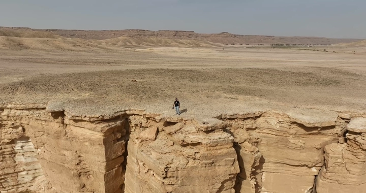 شاب يقف على حافة جبل طويق بالرياض، لقطة جوية.