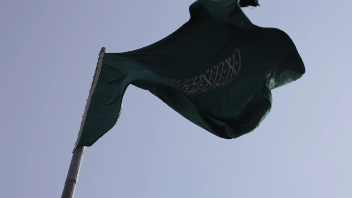 علم السعودية يرفرف في السماء مع غيوم، لقطة منخفضة.