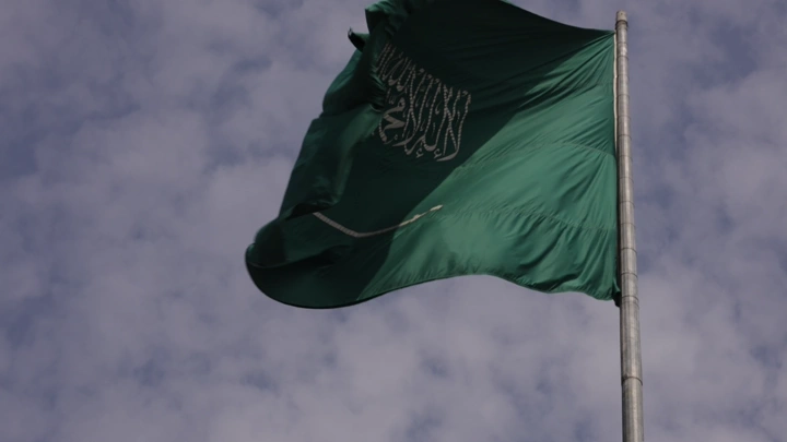 علم أخضر يرفرف مع غيوم في السماء، لقطة منخفضة.