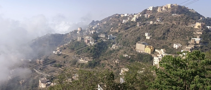 جبال فيفاء في جازان مع مباني وسط الضباب، منظر بانورامي.