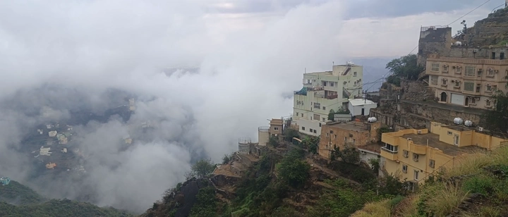 منازل على حفه جبل في فيفاء، جازان، في جو ضبابي، لقطة بانورامية.