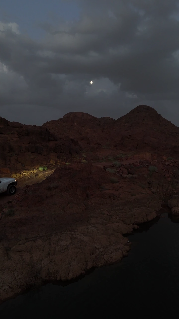 سيارة في منطقة جبلية تحت ضوء القمر، تصوير ليلي.