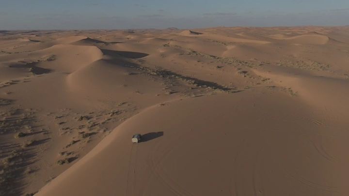 سيارة مجهزة تسير على الرمال، لقطة جوية.