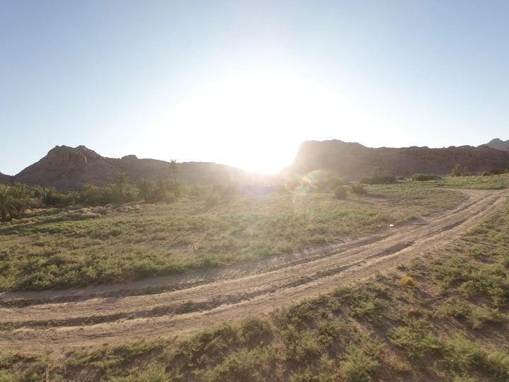 Sun between mountains and palm trees in Hail, aerial shot.